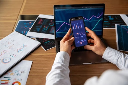 Man with multiple devices looking at trading charts